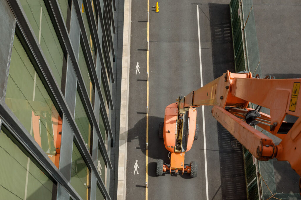 Aerial view of orange construction lift on road beside building.