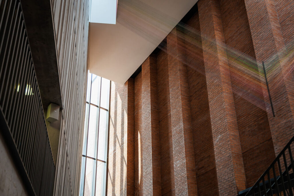 Architectural interior with brick walls, window, and colorful light beams.