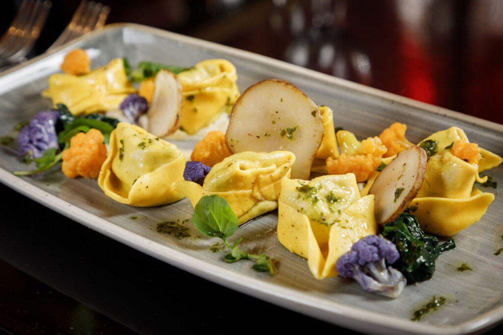 Artfully plated pasta with vegetables and mushrooms.
