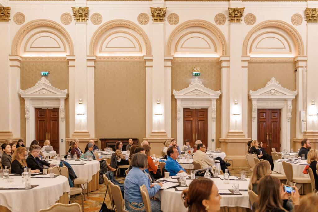 Audience at a formal conference in an ornate room.