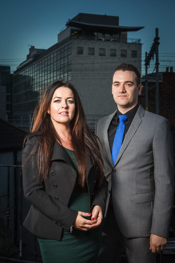 Business professionals standing outdoors with city background.