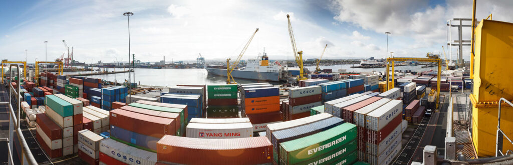 Busy shipping port with containers, cranes, and ships.