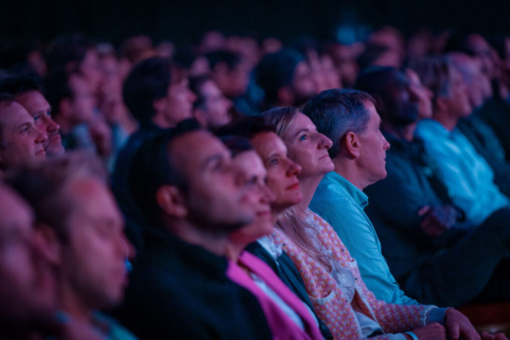 Captivated audience watching a show in a dark theater.