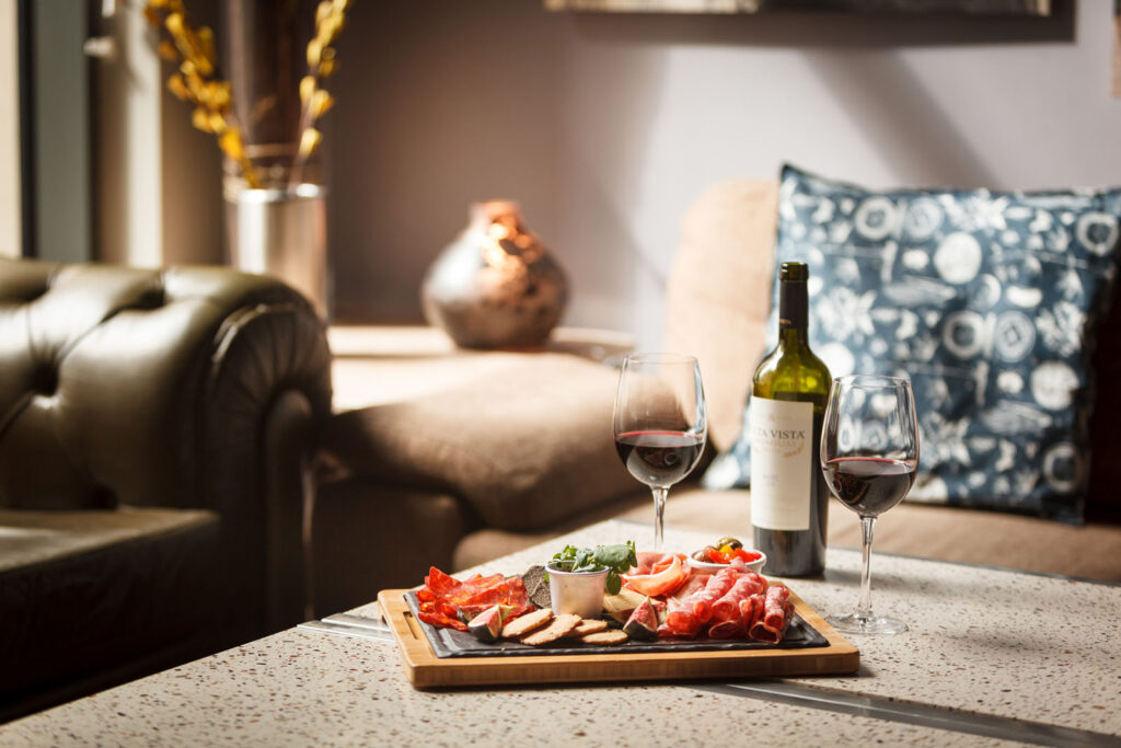 Charcuterie board and red wine in a cozy setting.
