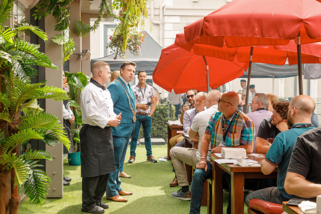 Chef and official speak at an outdoor gathering.
