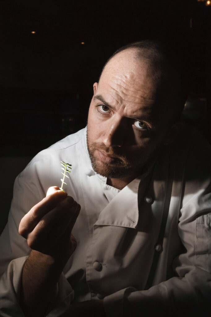 Chef intently holds a small green sprig.