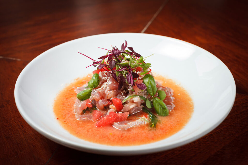 Colorful raw fish ceviche with microgreens and sauce.