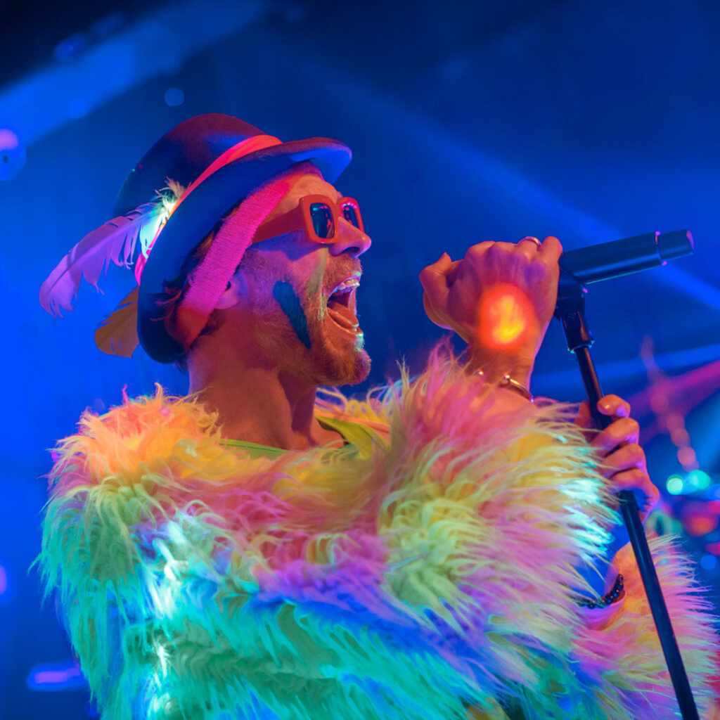 Colorful singer performing on stage with microphone.
