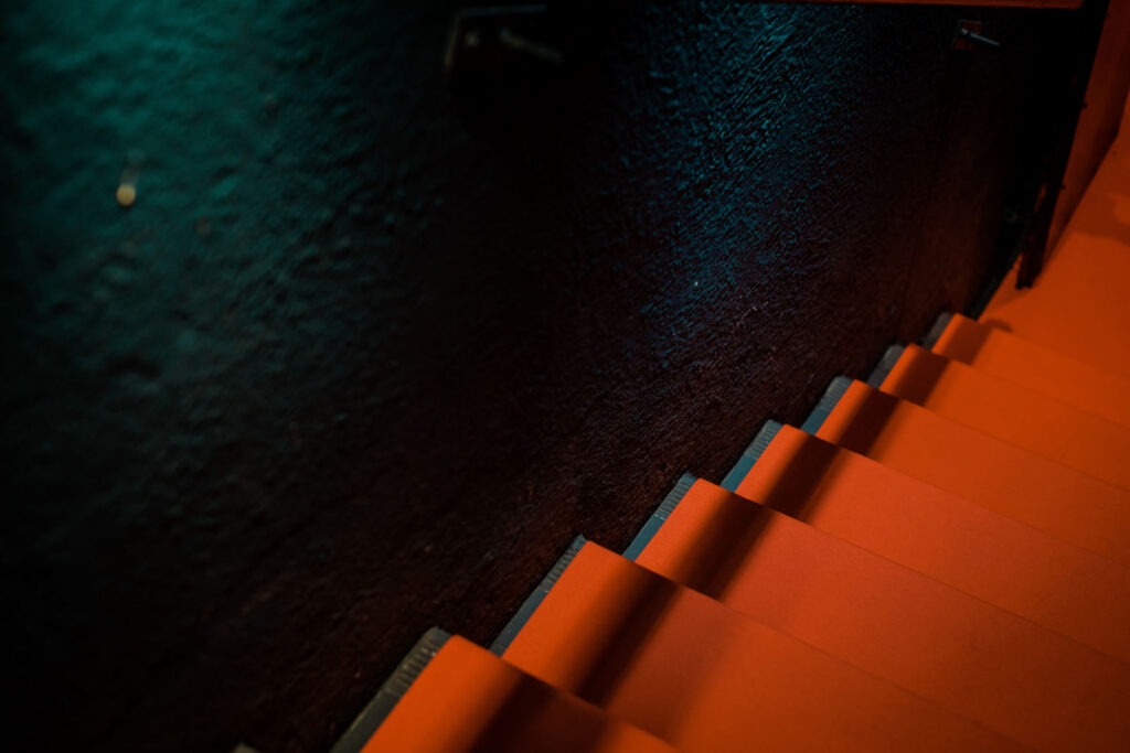 Contrasting orange stairs and dark teal wall.