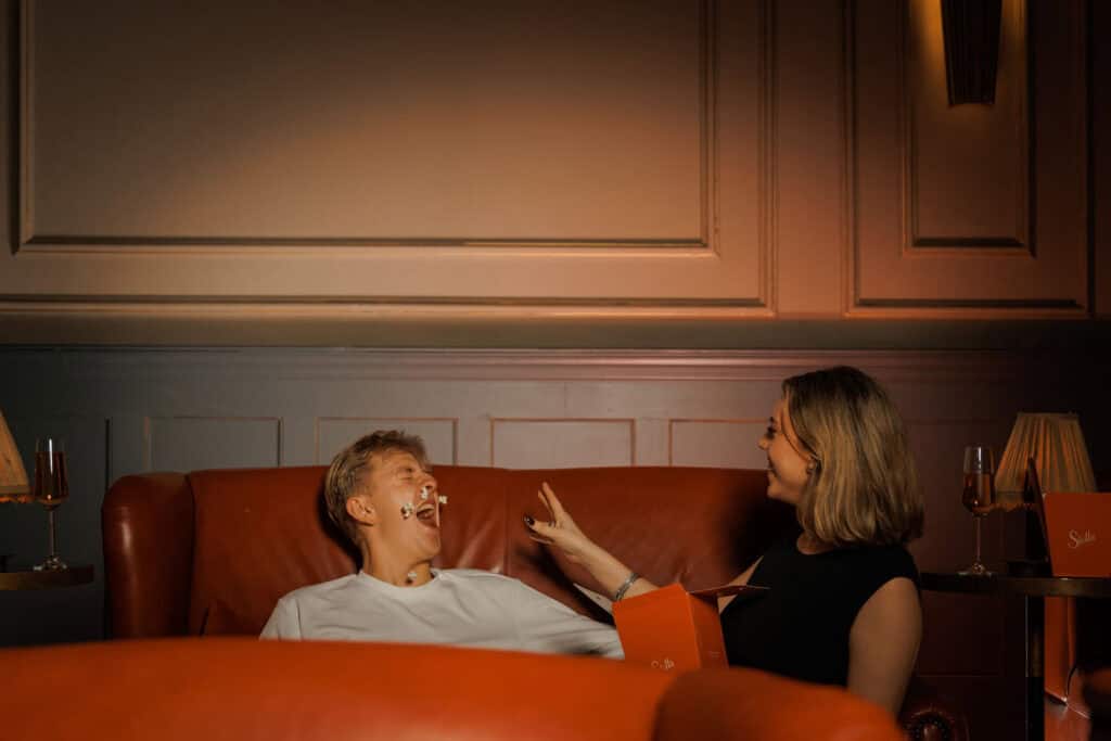 Couple laughing, man covered in popcorn.