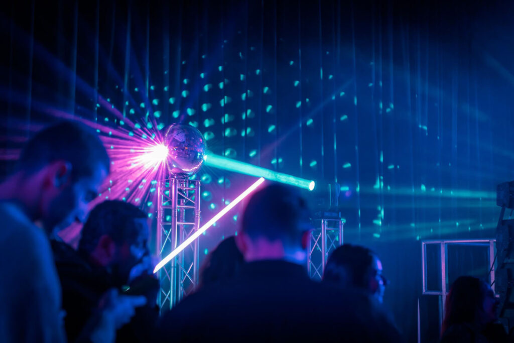 Disco ball and laser lights illuminate a lively party.
