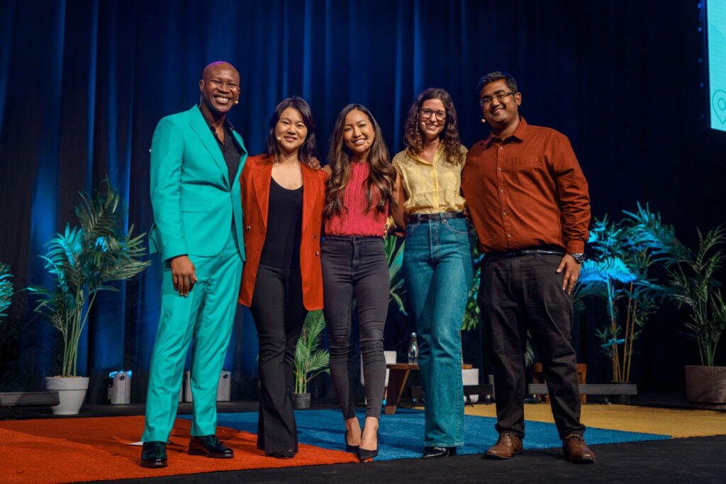 Diverse group of five people smiling on stage.
