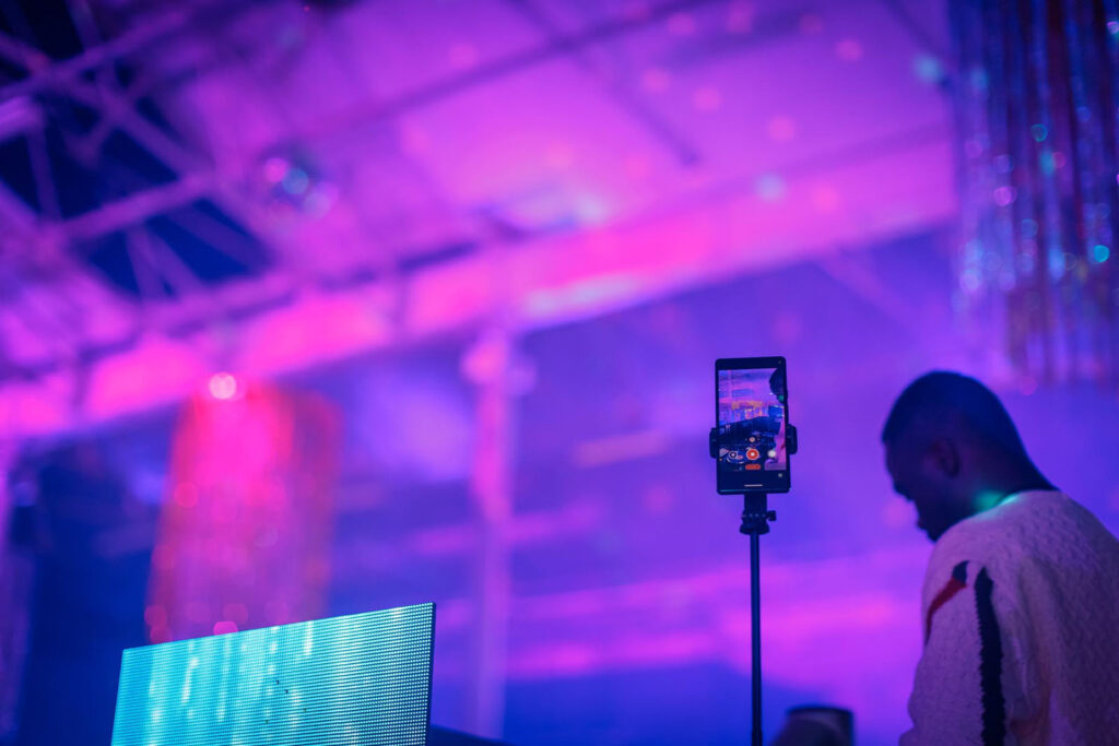 DJ set recorded by smartphone in a vibrant purple club.