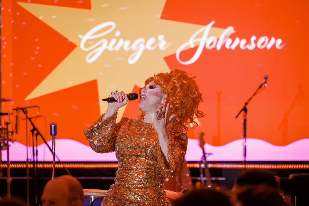 Drag queen Ginger Johnson performs on stage in a sequined dress.
