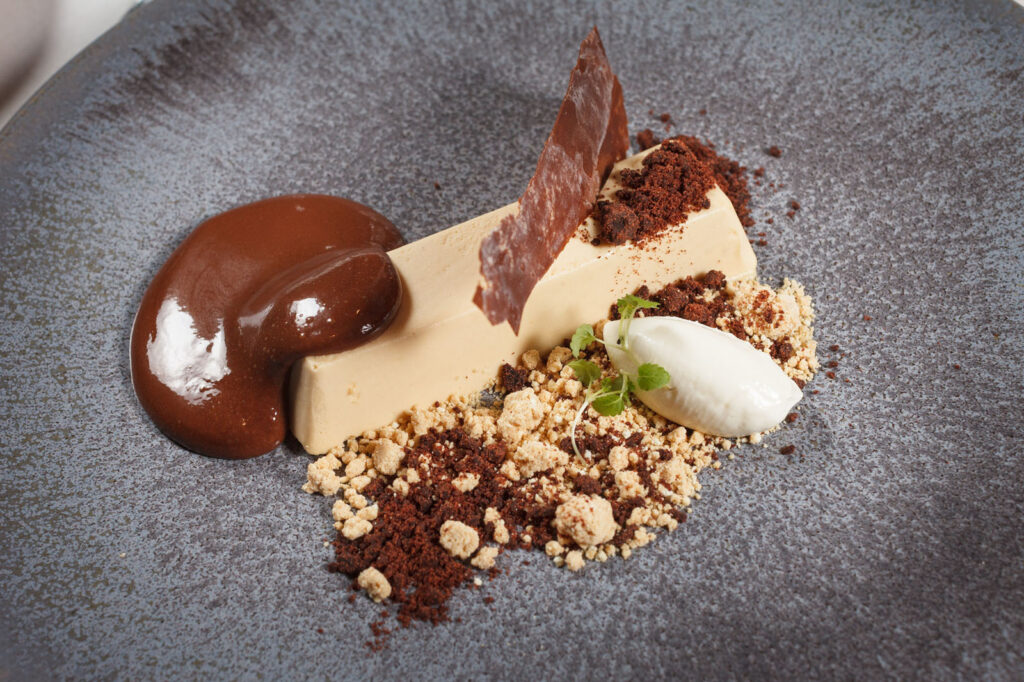 Elegant chocolate dessert with sauce, crumble, and cream.