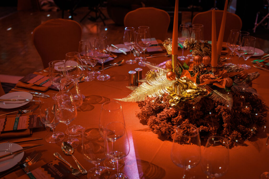 Elegant Christmas dinner table with golden centerpiece and candles.