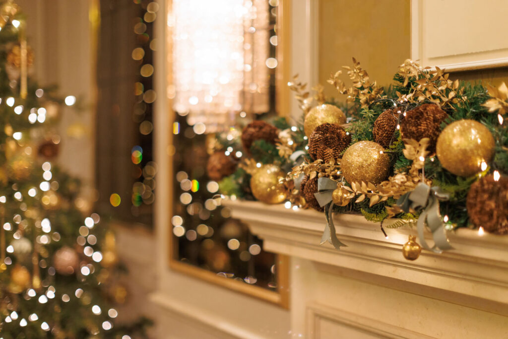 Elegant Christmas garland and tree with golden ornaments and lights.