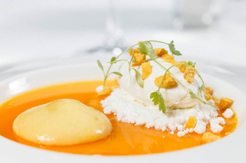 Elegant dessert featuring orange sauce, vanilla ice cream, and crunchy topping.