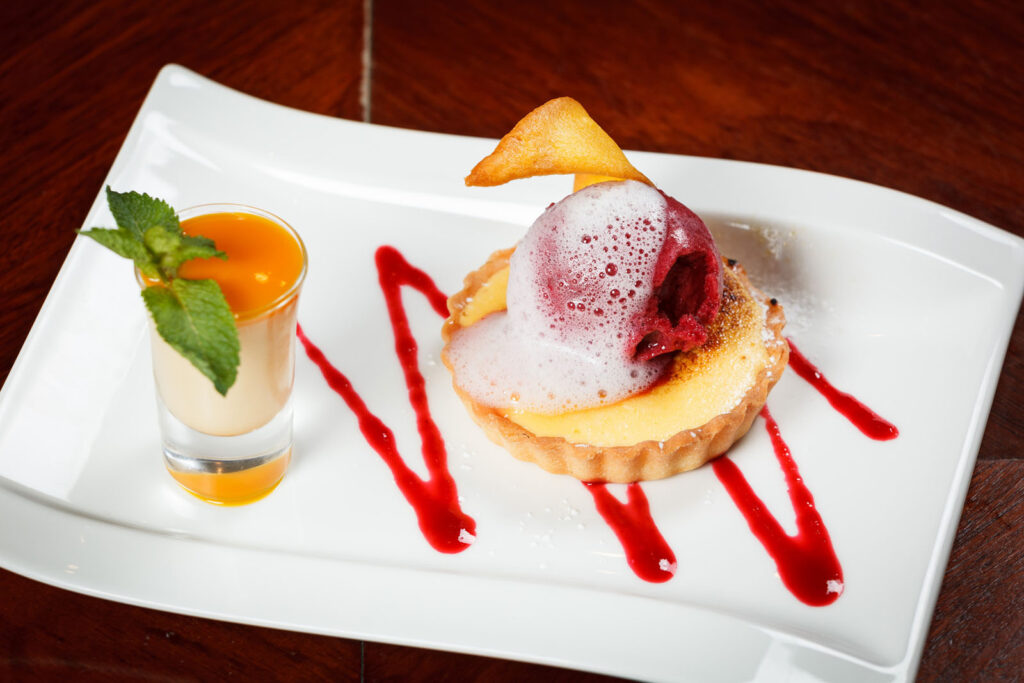 Elegant dessert: tart with sorbet, foam, and layered shot.