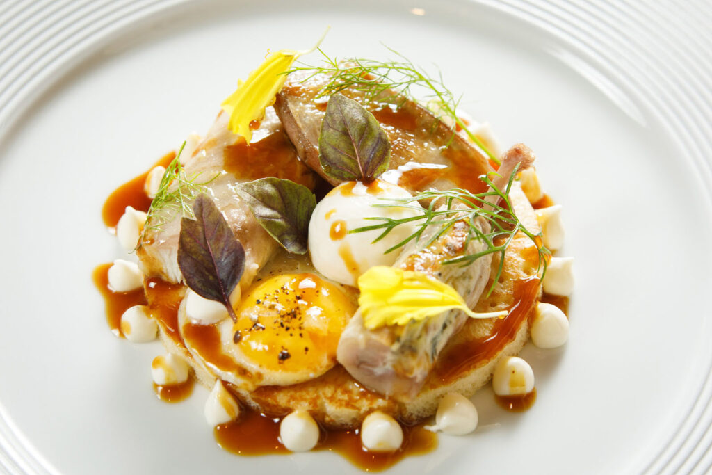 Elegant gourmet dish with meat, eggs, and sauce.