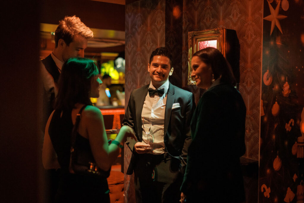 Elegant guests mingle and converse at a festive evening event.