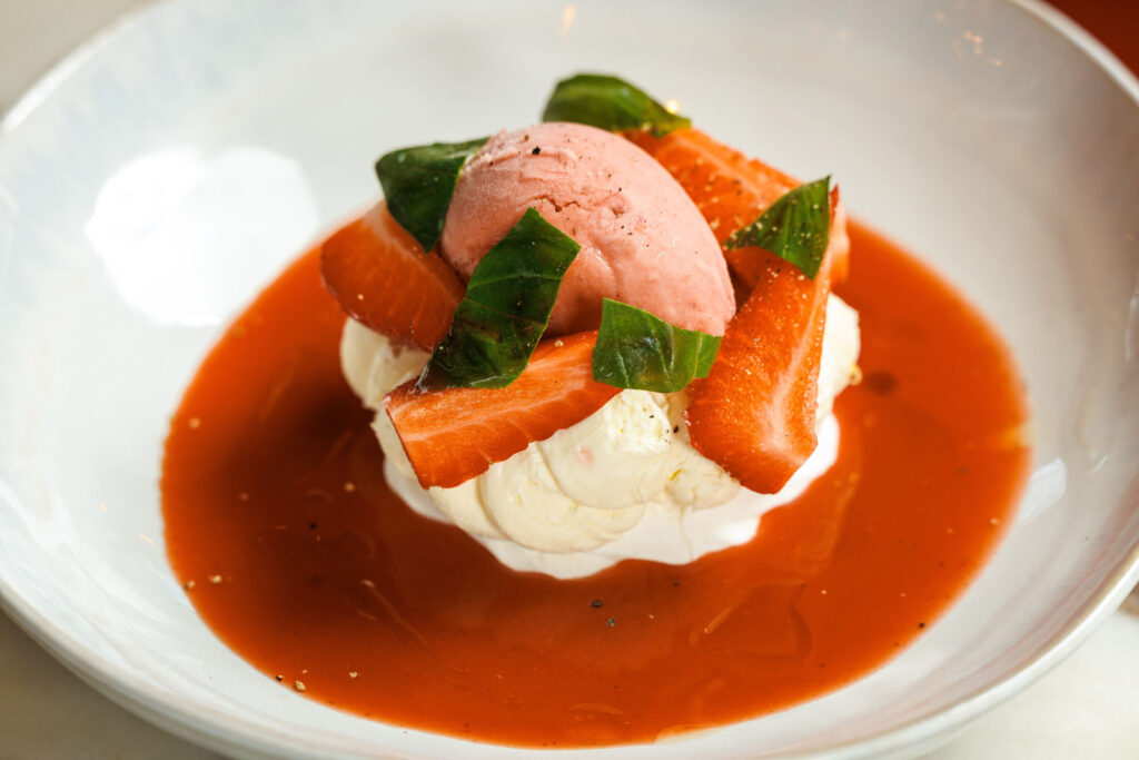 Elegant strawberry dessert with ice cream and basil.