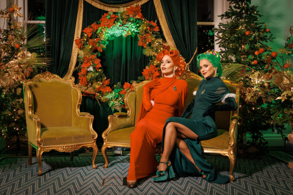 Elegant women in red and green amidst festive Christmas decor.