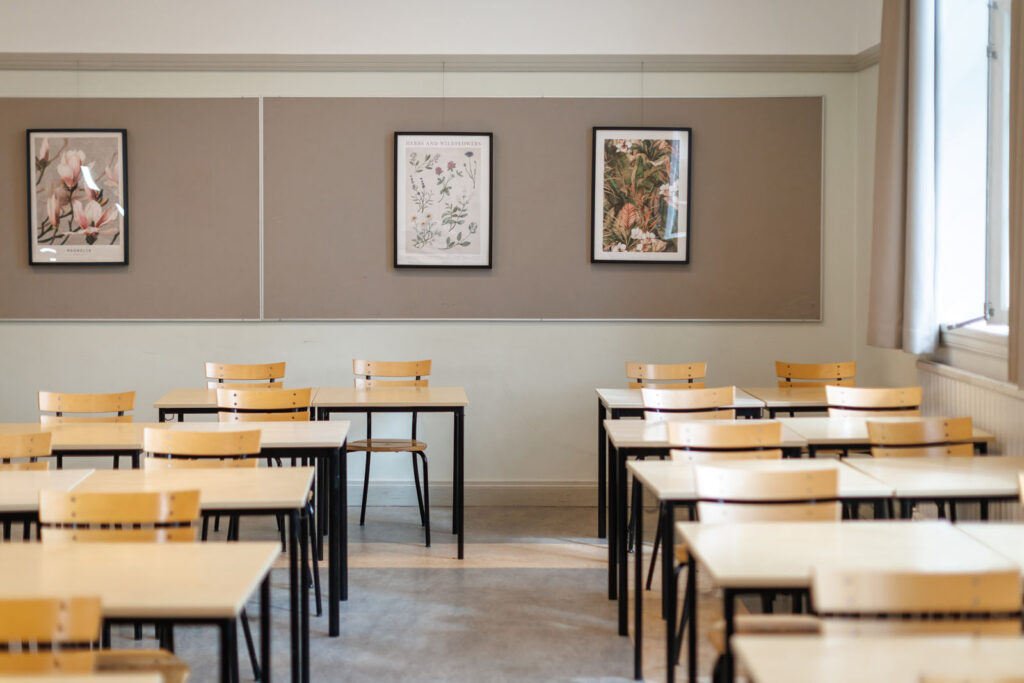 Empty classroom with desks, chairs, and botanical posters.