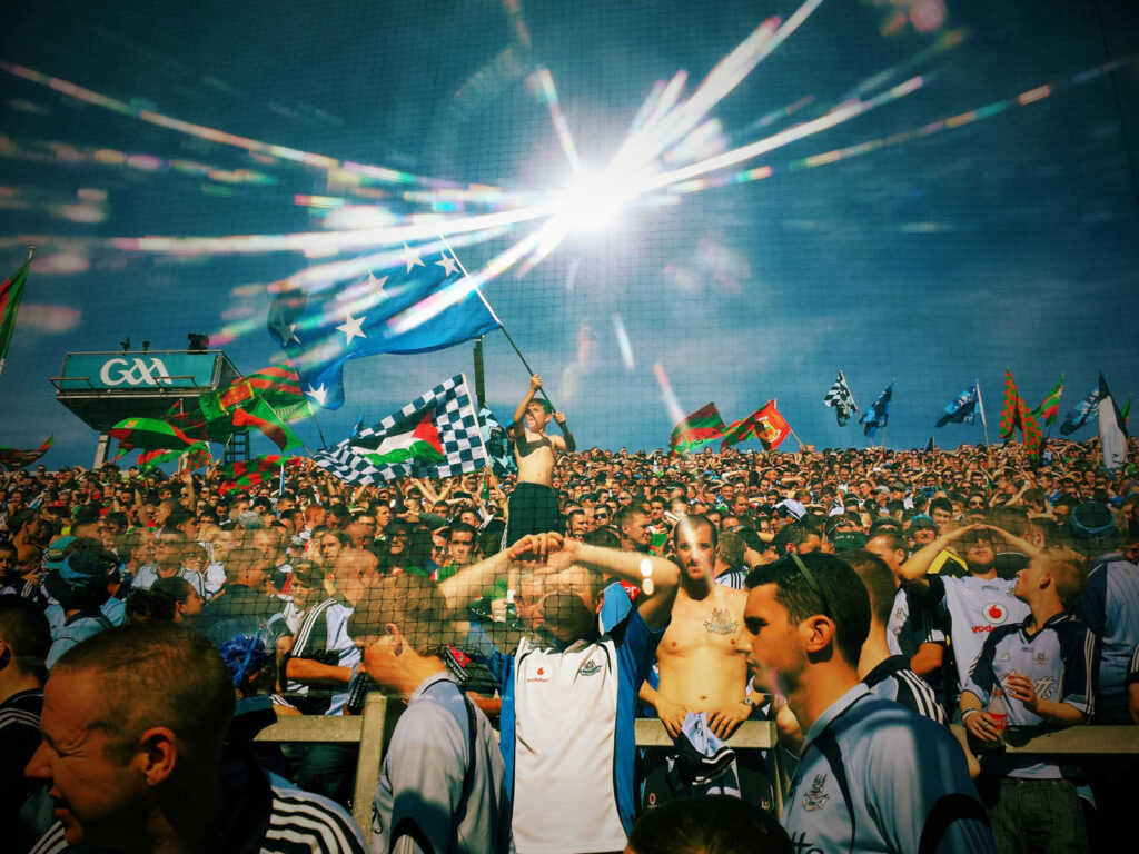 Enthusiastic crowd at a sunny GAA sporting event.