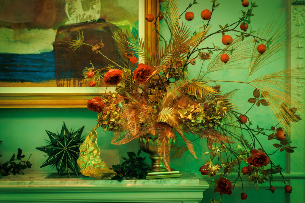 Festive floral arrangement with red roses and golden accents.