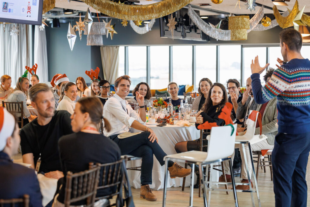 Festive office Christmas party with a speaker and attendees.