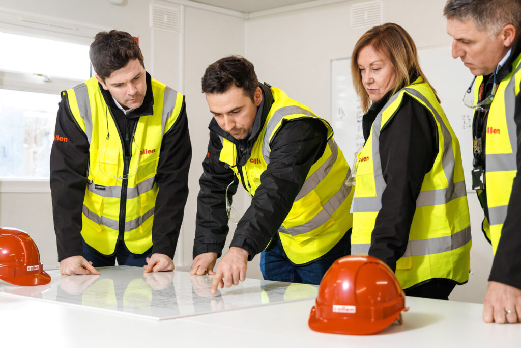 Four construction professionals reviewing blueprints together.