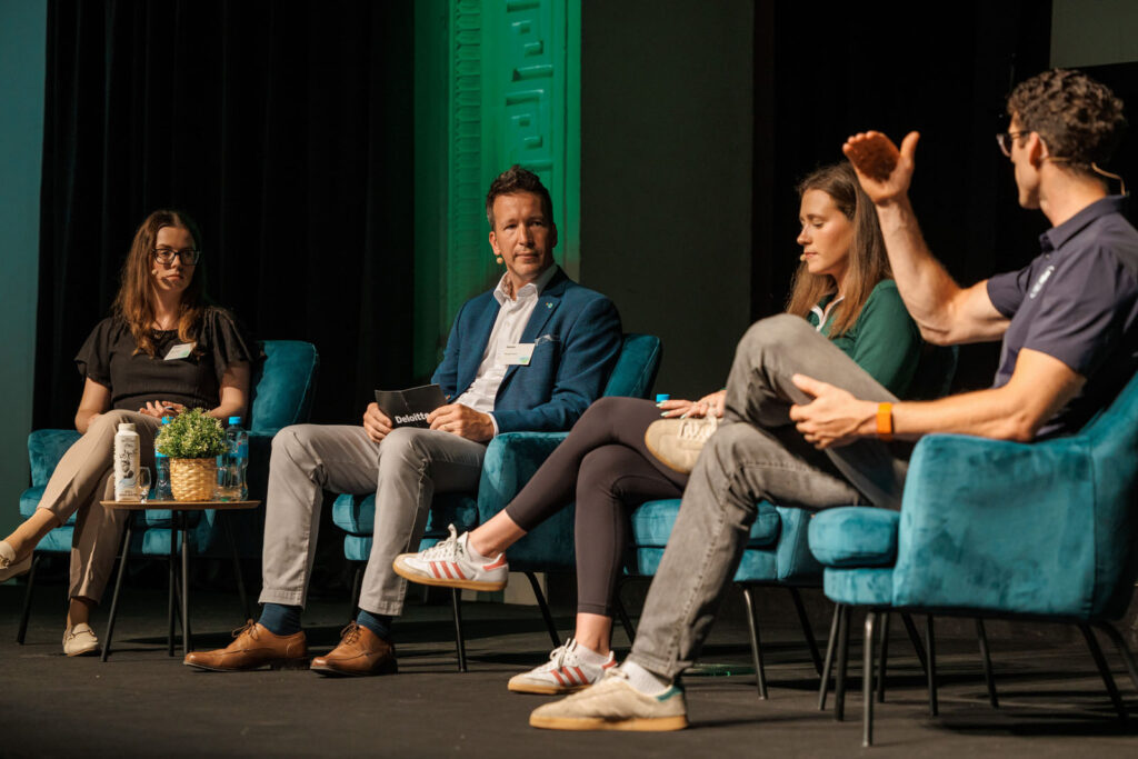Four speakers on stage during a panel discussion.