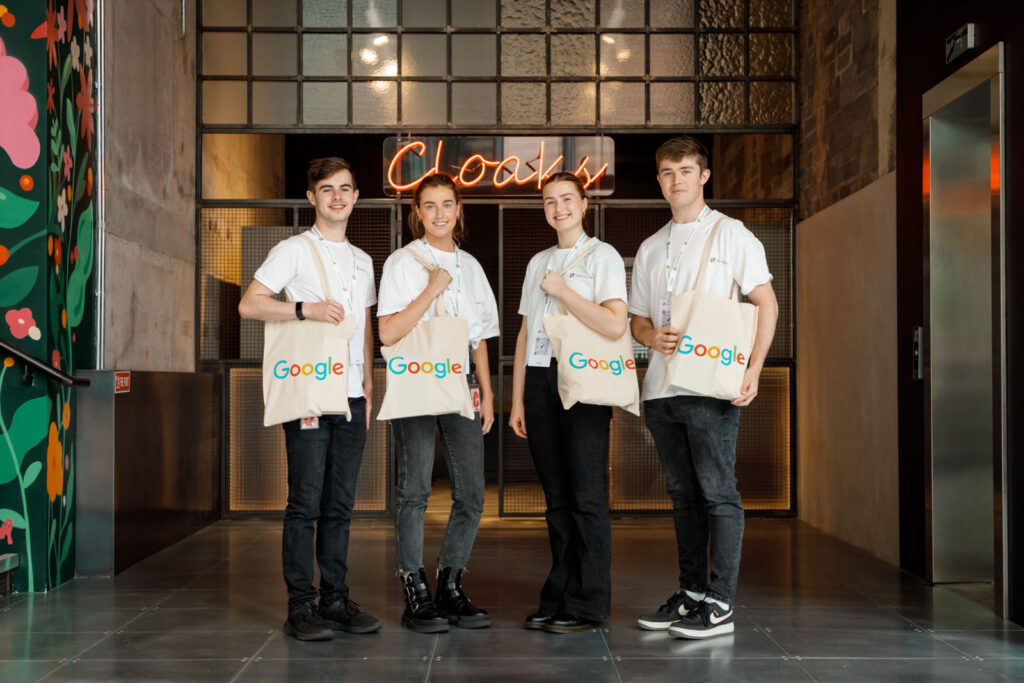 Four young people proudly display Google tote bags.