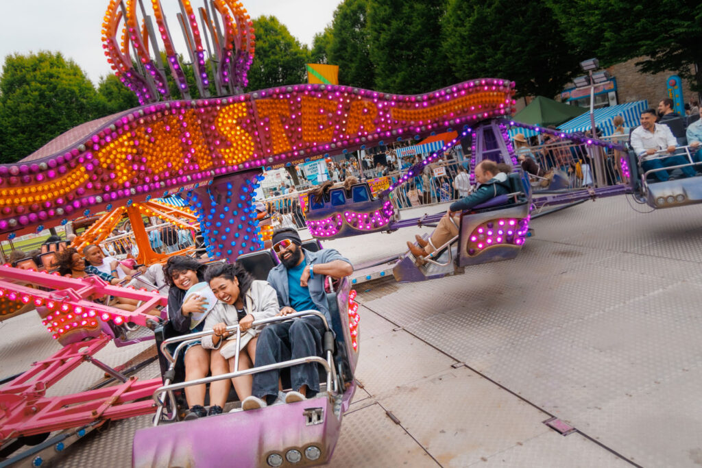Friends laughing on a colorful amusement park ride.