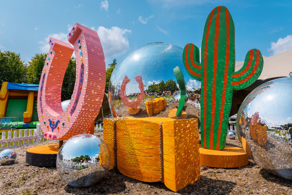 Giant disco balls, cactus, and horseshoe decorations outdoors.