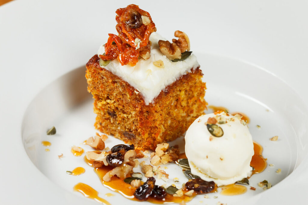 Gourmet carrot cake with ice cream, nuts, and candied carrots.