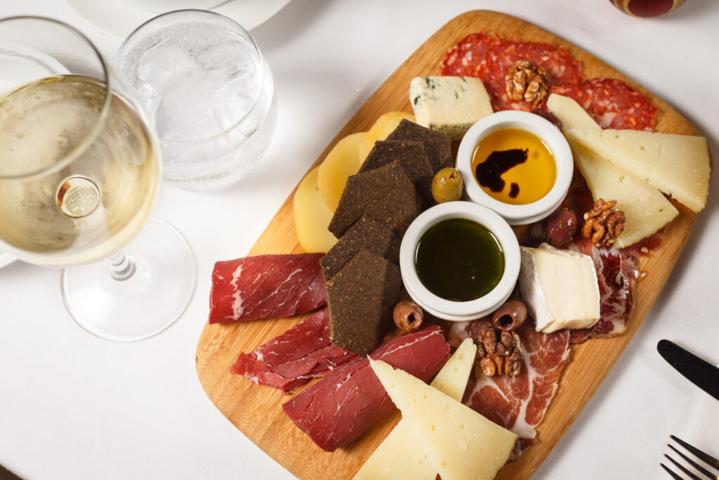 Gourmet charcuterie board with wine, cheeses, and cured meats.