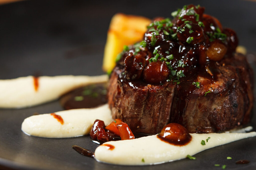 Gourmet steak with rich sauce, creamy puree, and roasted potato.
