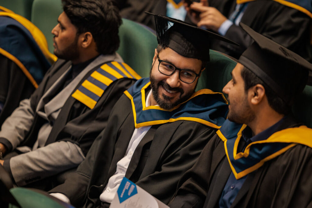 Graduates smiling and conversing at a ceremony.
