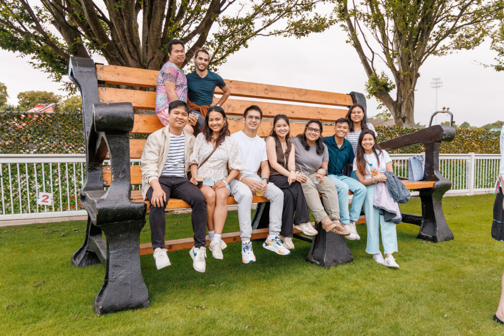 Group of friends smiling on a giant park bench.