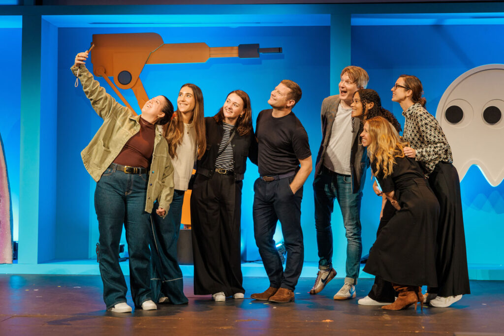 Group of friends taking a selfie on a blue stage.