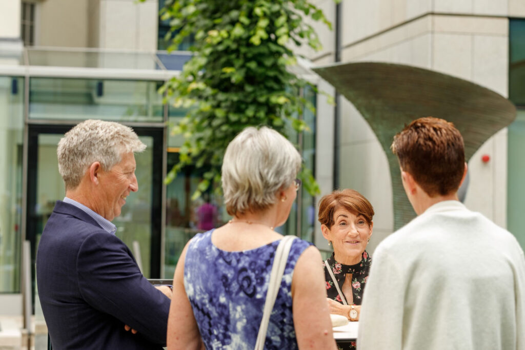 Group of people chatting and smiling outdoors.
