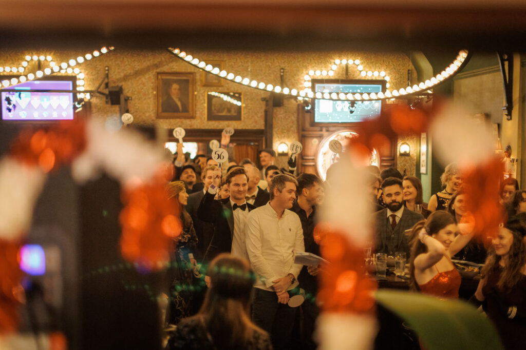 Guests holding numbered paddles at a lively indoor event.