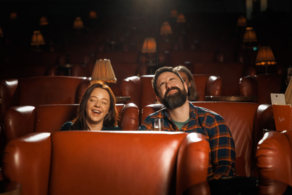 Happy couple laughing in a dimly lit cinema.