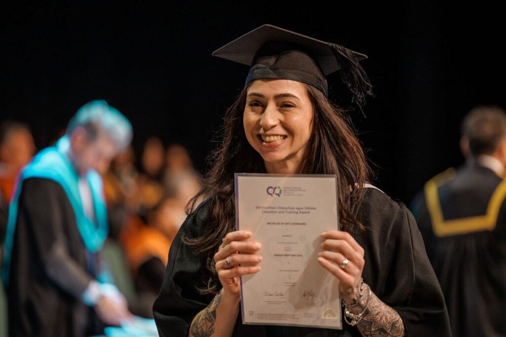 Happy graduate holding diploma at ceremony.