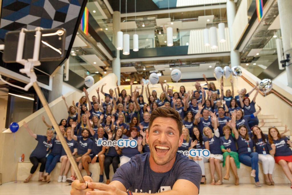 Happy LinkedIn team takes group selfie on office stairs.