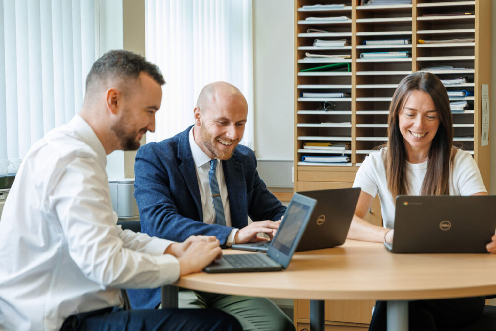 Happy team collaborating on laptops in office.