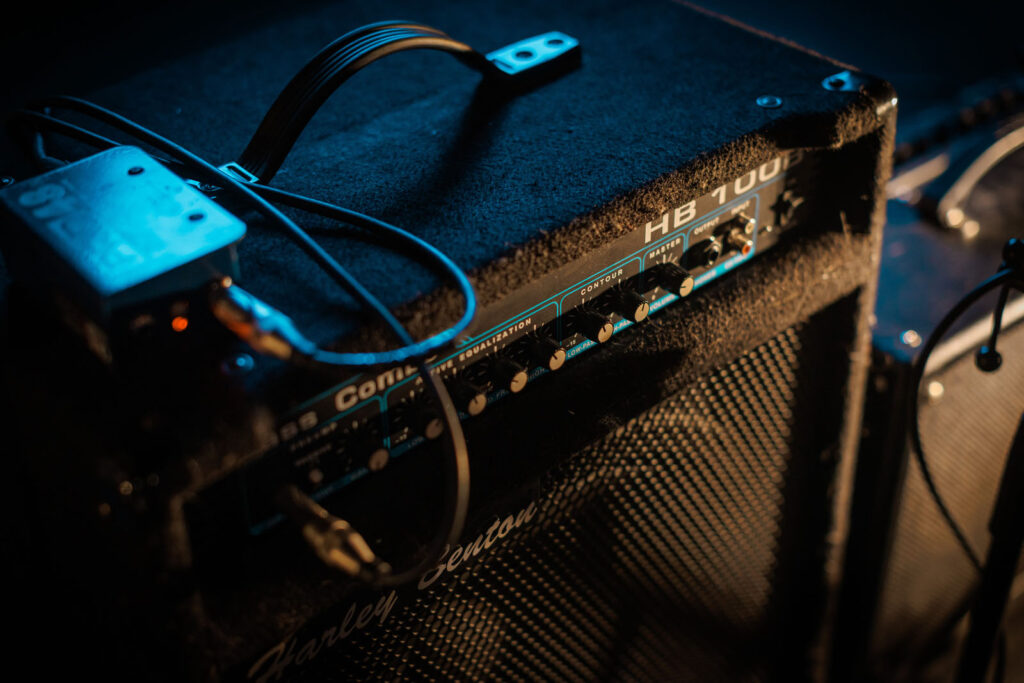 Harley Benton bass amplifier with controls and cables under blue light.