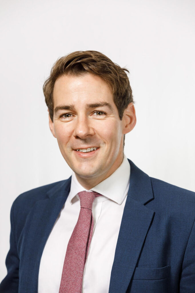 Headshot of a smiling man in a suit.